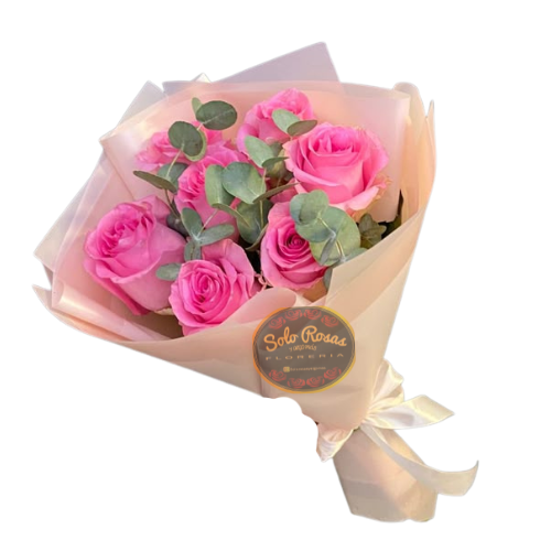 Ramo de 7 rosas rosadas envueltas en papel coreano color marfil con follaje verde y lazo blanco, ideal para regalo elegante y delicado.