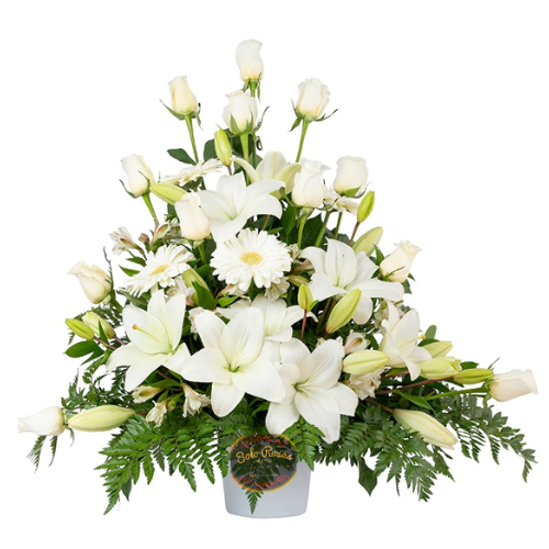 Arreglo floral con 12 rosas blancas, 8 lilium blancos y 2 gerberas en base decorativa elegante.